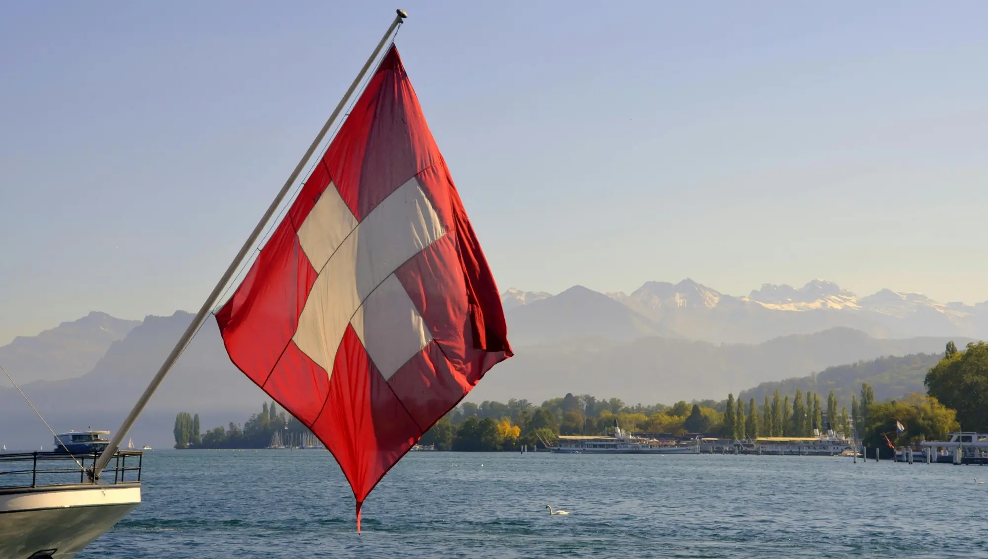 Swiss flag over the lake with the Alps in the background